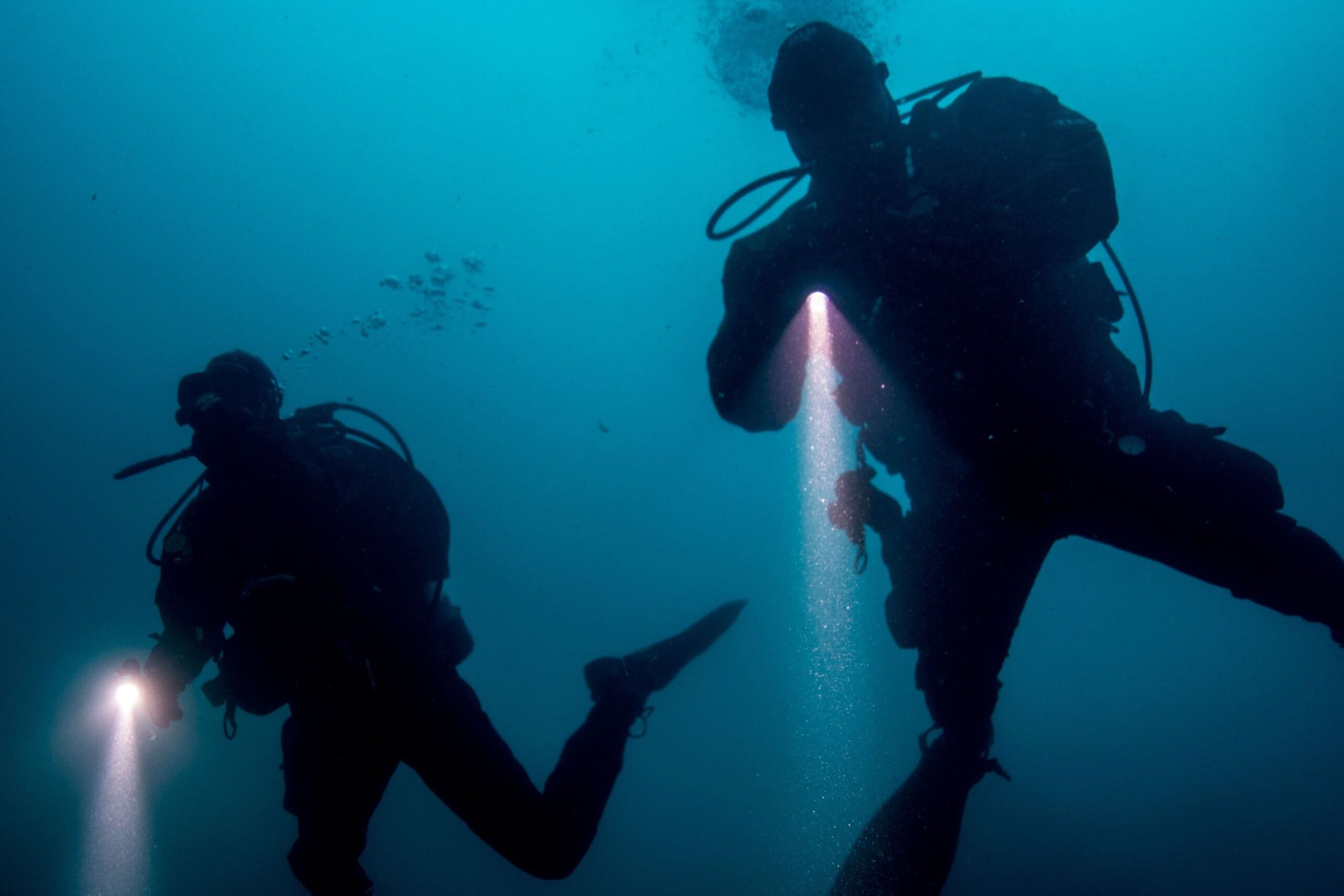 two divers in the water with a flashlight